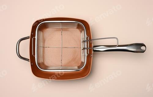 Preview: Empty copper deep frying pan with grill grate on beige background. View from above