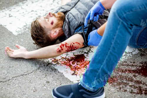 Preview: Man applying first aid to the bleeding person on the road