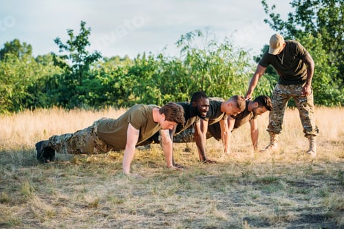 Preview: tactical instructor examining multicultural soldiers in military uniform doing push ups on range