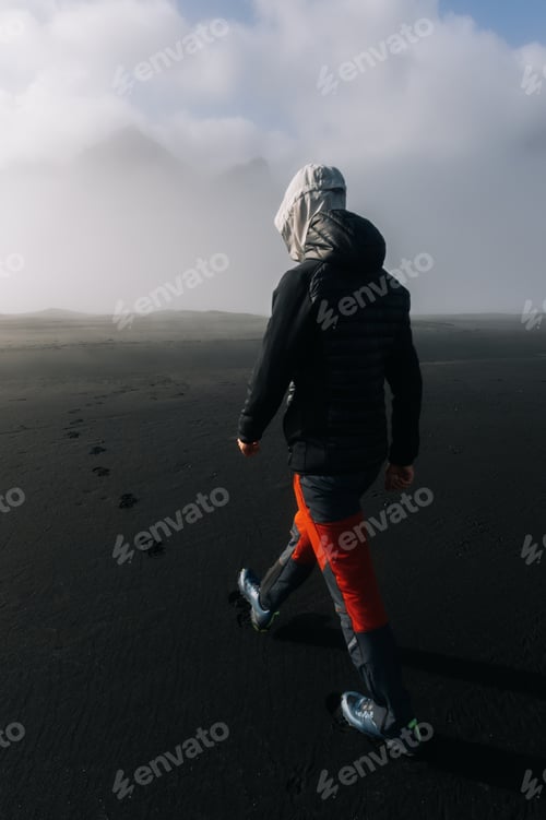 Preview: A man is walking on the sand on a beach in nature in cloudy weather.