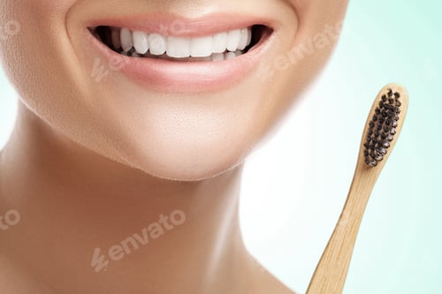 Visualização: Boca feminina com dentes brancos e escova de dentes de bambu