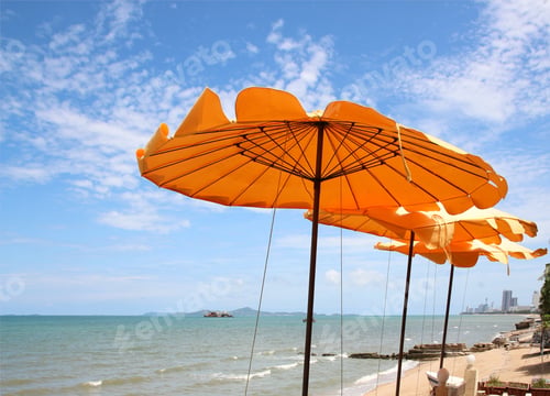 Preview: Yellow beach umbrella on blue sky and white clouds
