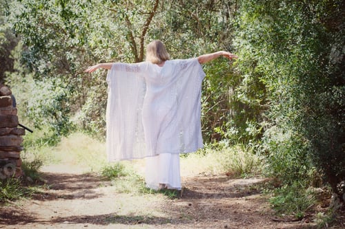 Preview: Woman dressed in white walking from behind in a nature forest