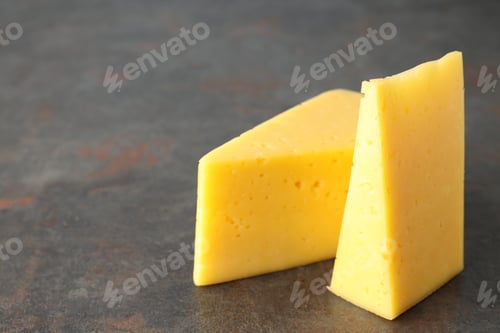 Vista previa: Two pieces of hard cheese on textured background