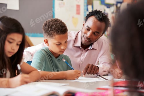 Preview: Male teacher working with elementary school boy at his desk