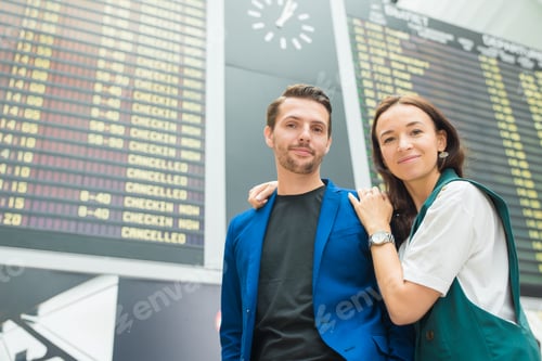 Preview: Young couple in international airport looking at the flight information board