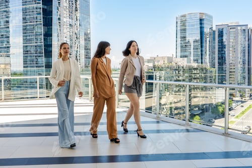 Preview: Three businesswomen walking on a tower building terrace