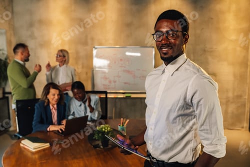 Preview: Smiling multiracial businessman with tablet posing at office on meeting