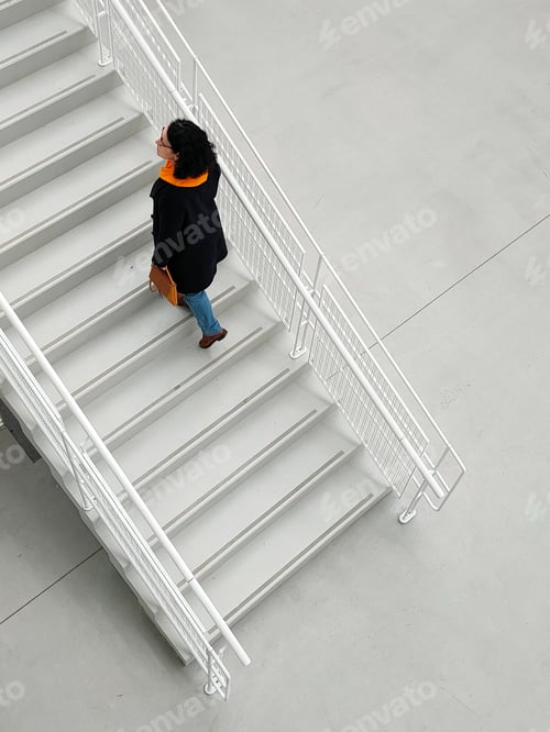 Preview: mature woman in fashionable clothes climbs the white stairs