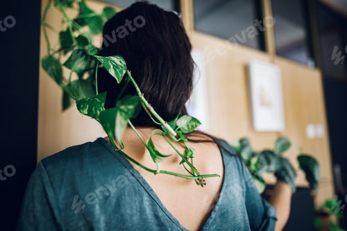 Preview: Fashionable young woman taking care of her house plants