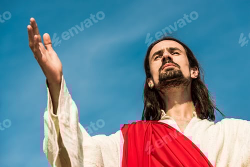Preview: low angle view of man with outstretched hand against blue sky