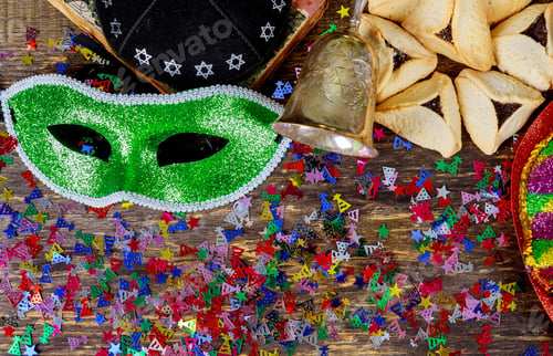 Preview: Purim jewish holiday with purim mask and purim a noisemaker on a vintage wood background with kosher