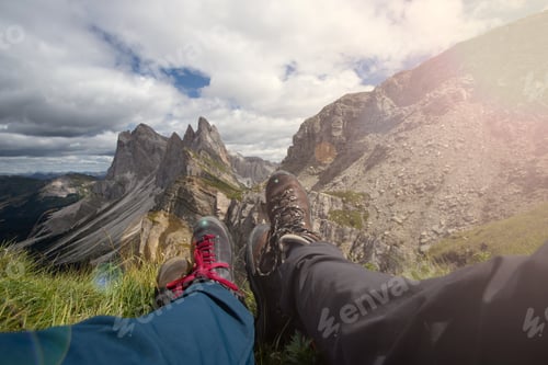 Preview: Trekking boots of a hiker couple while sitting on top of a mountain in Seceda, Dolomites, Italy