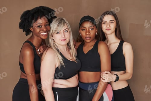 Preview: Group of multi ethnic women standing in the studio against brown background