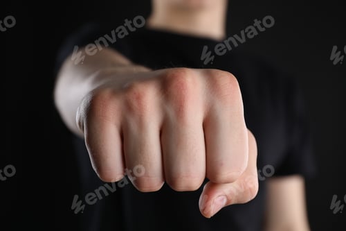 Preview: Man showing fist with space for tattoo on black background, selective focus