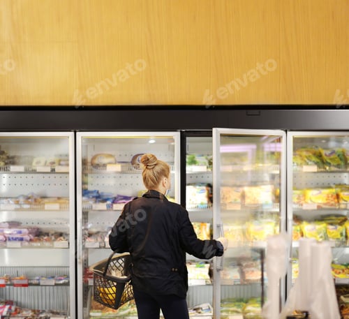 Preview: Woman Choosing Frozen Food From A Supermarket Freezer. Purchasing A Packet Of Meat At The