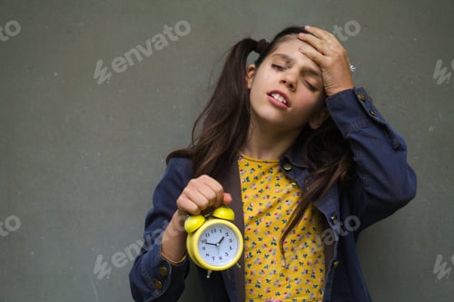 Preview: Closeup shot of a young Caucasian female holding an alarm clock and feeling forgetful