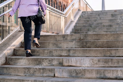 Preview: legs of senior woman walking up stairs at city
