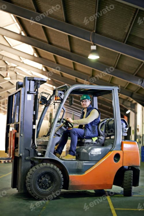 Man Driving Forklift Inside a Large Warehouse