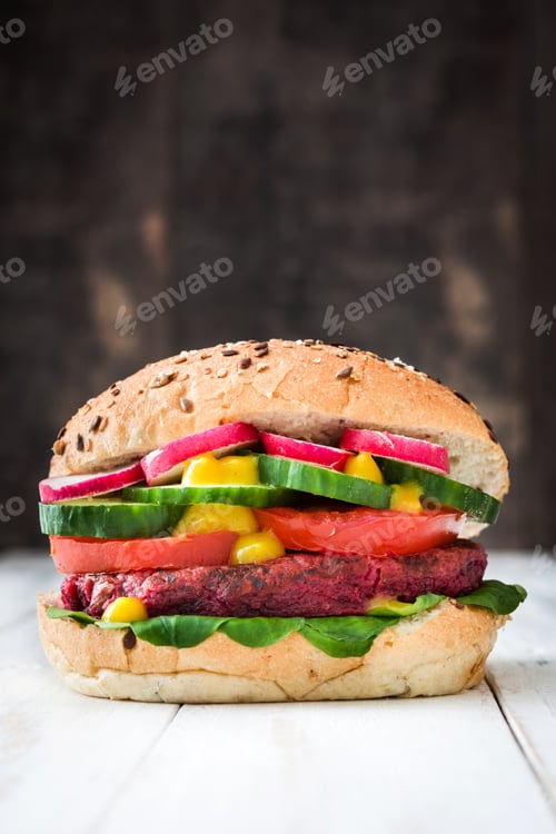 Preview: Delicious vegetarian beetroot burger with mustard, fresh vegetables and seeds on white table
