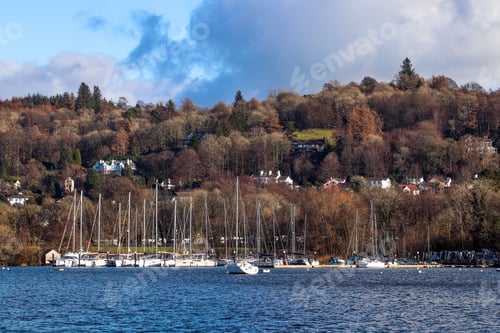 Preview: Landscape shot of fishing boats on the lake against the colorful autumn trees in Lake District, UK