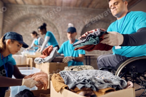 Preview: Group of volunteers organizing donated clothing in cardboard boxes at community center.