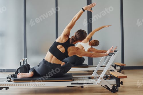 Preview: Two women in sportive wear and with slim bodies have fitness yoga day indoors together