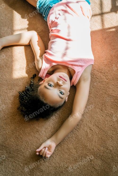 Preview: Girl laying on living room carpet in the sunlight