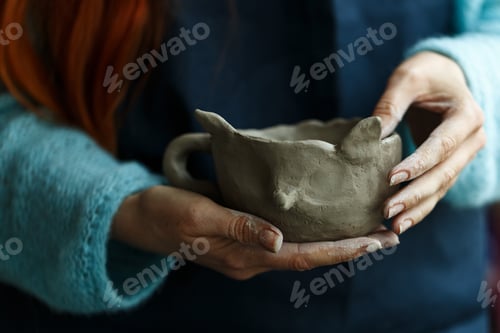 Preview: Woman potter in apron molding clay cup.Hands of professional ceramist create pottery crockery at