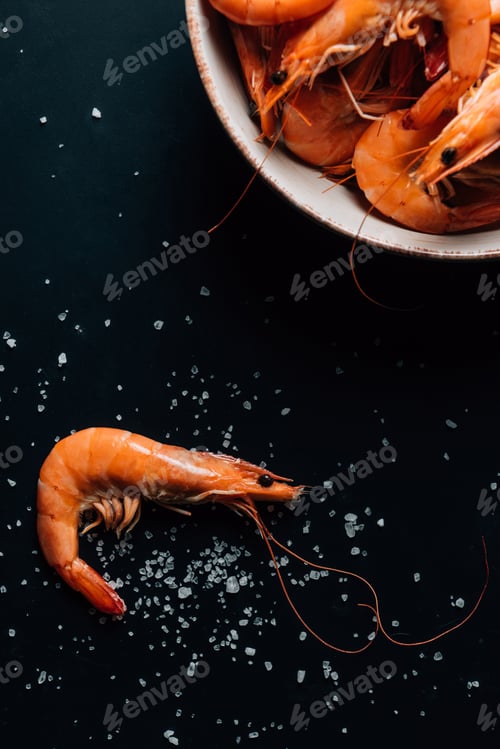 Preview: top view of plate with shrimps on dark table with salt
