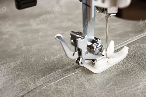 Preview: sewing machine with special presser foot makes a seam on grey leather. sewing process close up