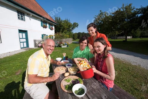 Preview: Germany, Bavaria, People at table in garden preparing food