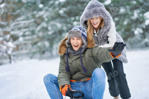 Preview: Couple having fun with sledge on snow in winter