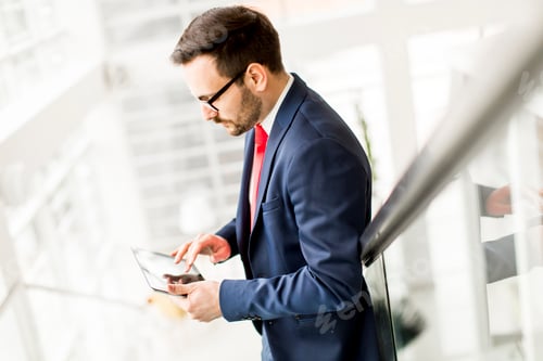 Preview: Young man with tablet on stairs in modern office