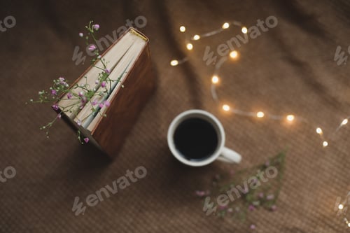 Preview: A book with flowers and cup of coffee on dark background top view