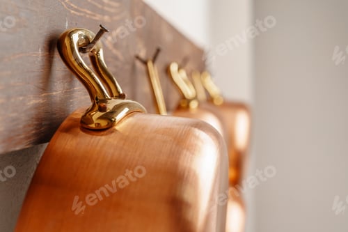 Preview: Row of shiny clean copper pans, different size, hung on wooden plank