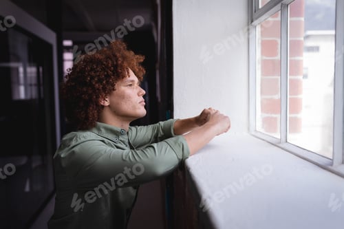 Preview: Portrait of mixed race businessman standing in office and looking at window