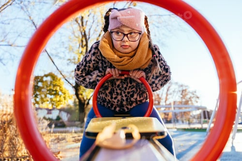 Preview: Girl with Down syndrome framed by red circle at playground