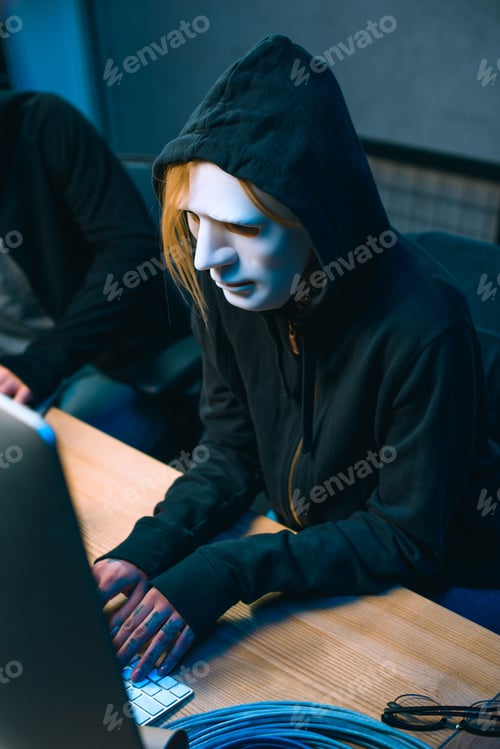 Visualização: high angle view of hacker in mask working with computer to develop malware