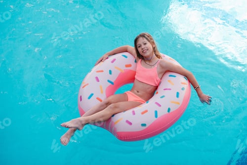 Preview: Beautiful young girl with inflatable donut in swimming pool