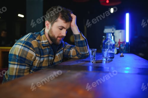 Preview: Sad man sitting at bar counter, alcohol addiction
