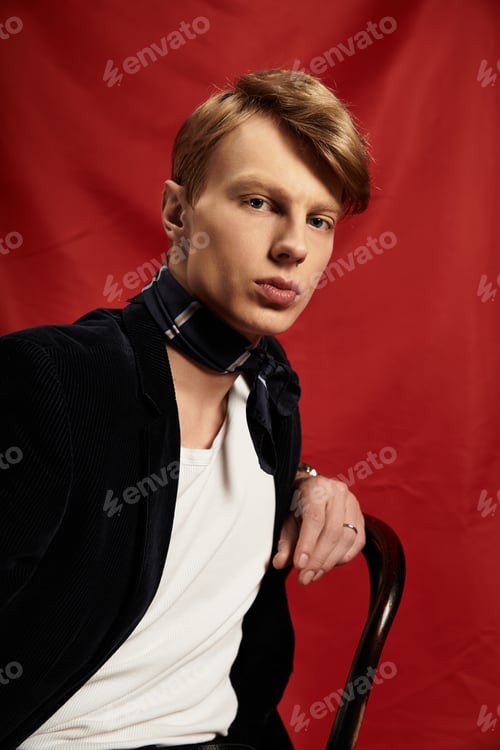 Preview: Young man embodies modern masculinity with charm against a vibrant red background