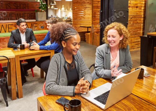 Preview: two multiracial businesswoman sitting in front of a laptop working in co-working space