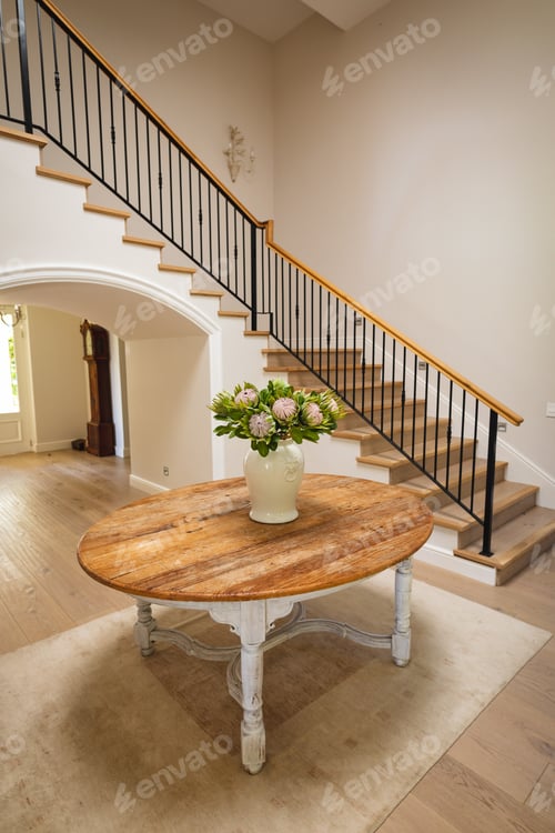 Preview: General view of house interior with table and vase with flowers in spacious hallway and staircase