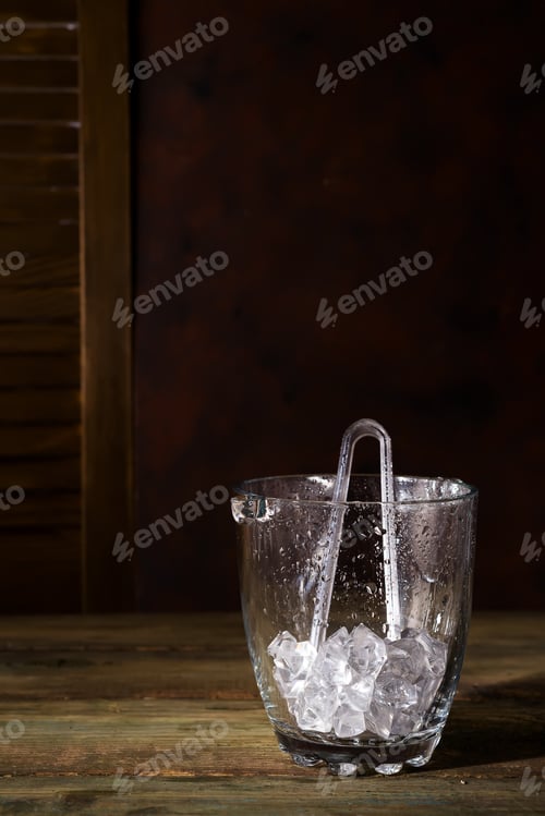 Preview: Champagne bucket full with ice on dark wooden background, shadows and copy space
