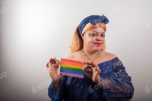 Preview: African lesbian posing with rainbow flag, she is dressed with african clothes, studio portrait
