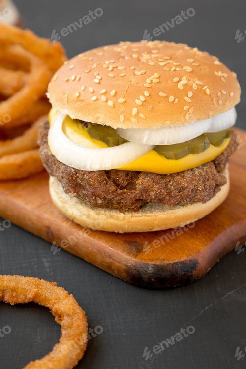 Preview: Homemade Mississippi Slug Burgers with onion rings on a rustic wooden board on a black surface