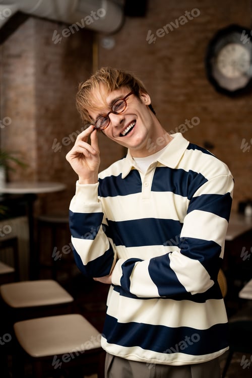 Preview: Charming young man enjoys a moment in a modern cafe setting with stylish flair