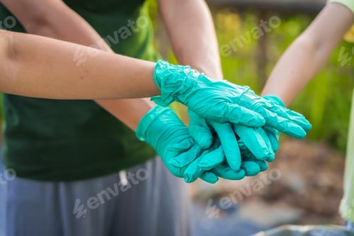 Preview: Close-up of female hands from a family collecting plastic waste and bottles from the ground