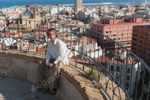 Preview: Young man sitting on a rooftop with Alicante in the background, Spain
